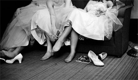 Photo of women in fancy dresses with shoes off, rubbing sore feet